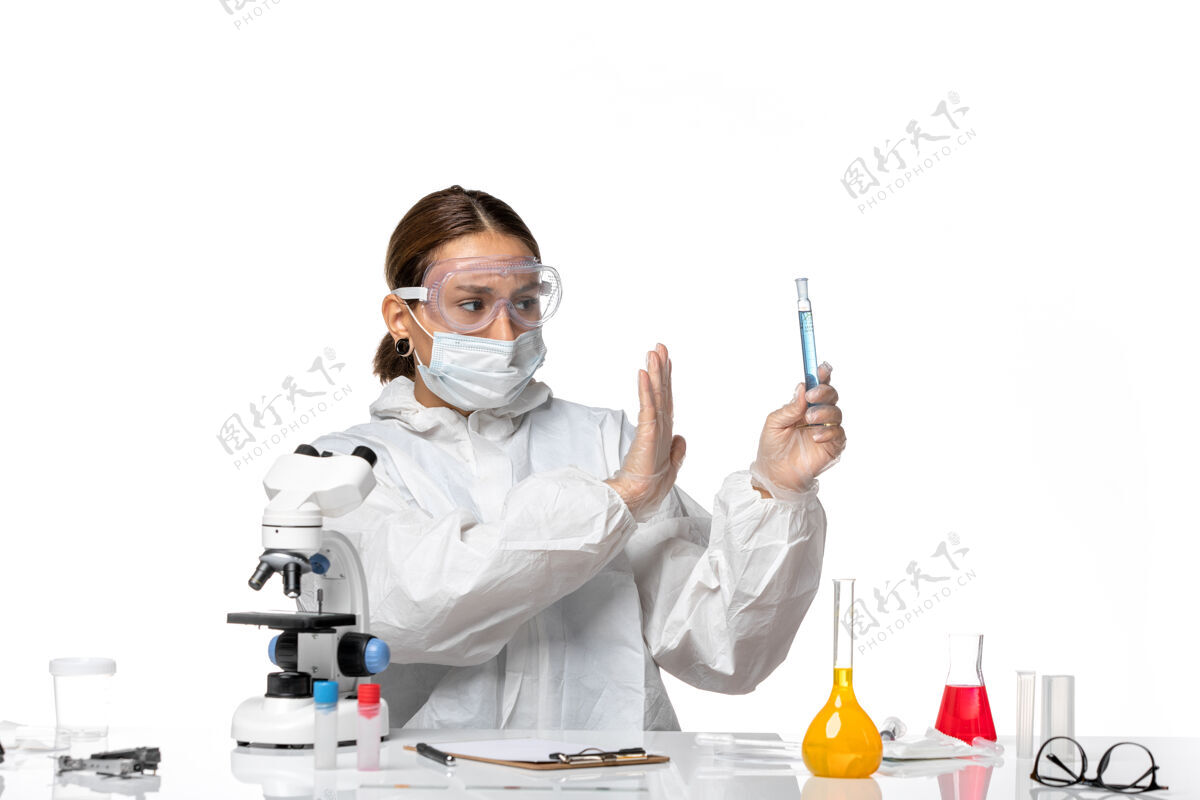 停止正面图：女医生穿着防护服 戴着口罩 拿着装有白色背景病毒溶液的烧瓶——大流行冠状病毒医生病毒实验室