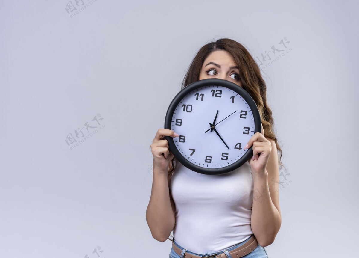 隐藏印象深刻的年轻漂亮的女孩拿着时钟 躲在它后面看着右边的复制空间复制时钟年轻