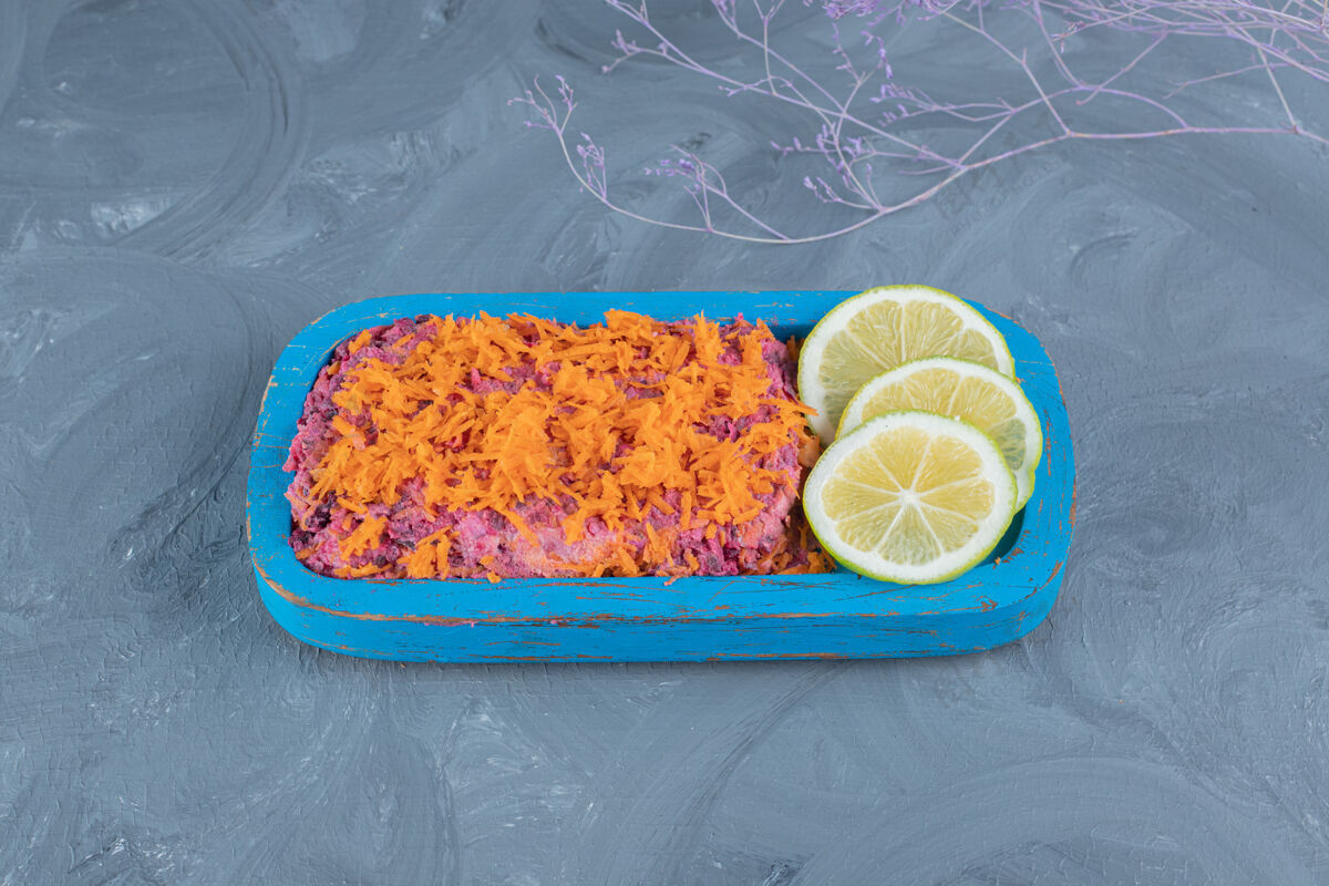 美味胡萝卜核桃甜菜沙拉配柠檬片放在大理石桌上装饰美味顶部