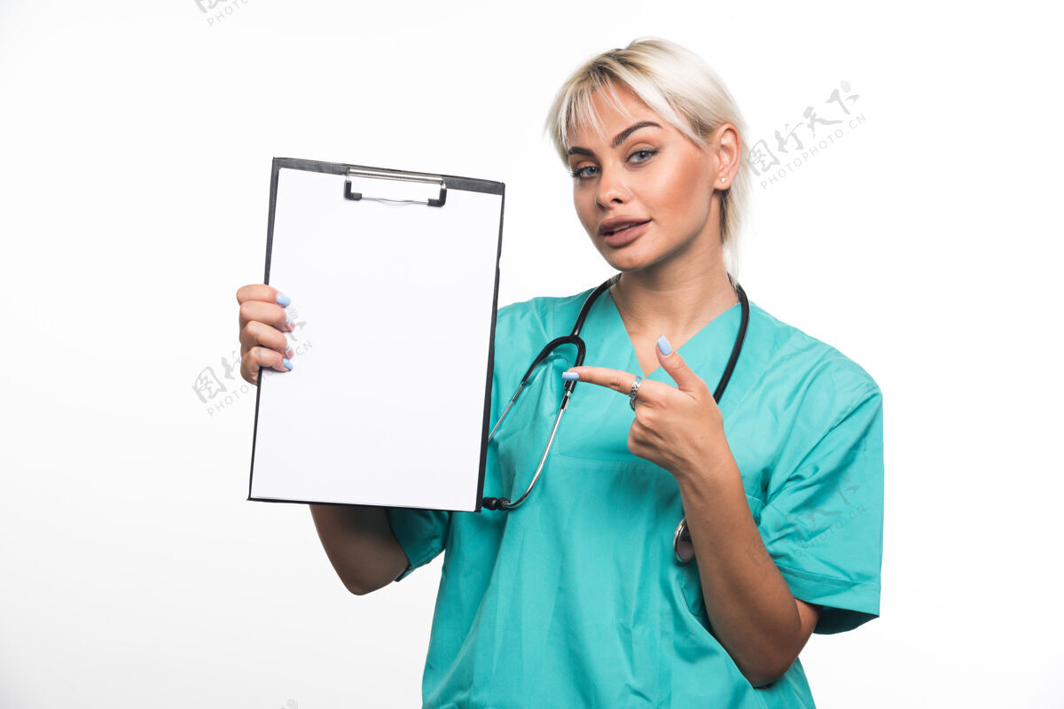 医生女医生拿着剪贴板指着白墙上的手指文件夹微笑站着