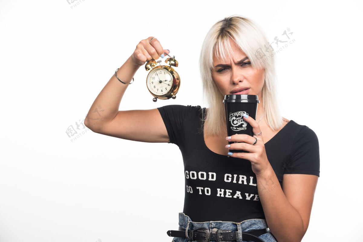 姿势年轻女子拿着钟 从白墙上的咖啡杯里啜了一口肖像成人严肃