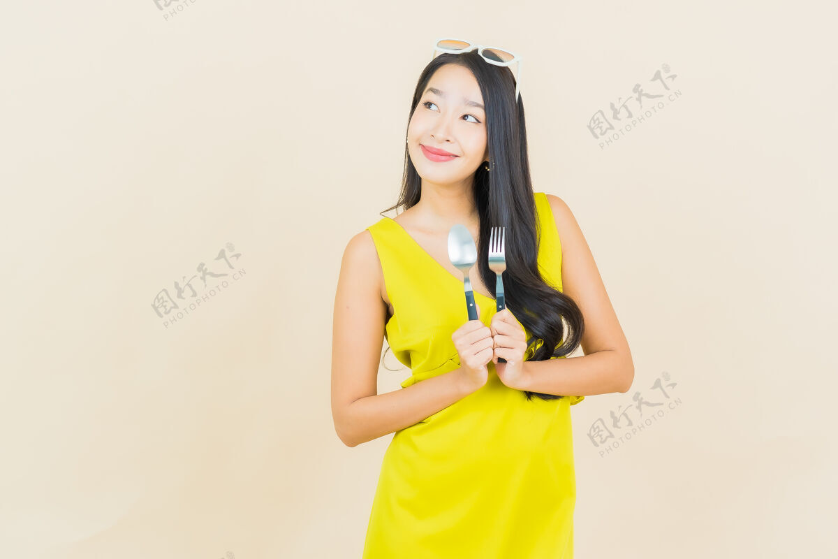 女孩画像美丽的亚洲年轻女子在彩色墙上用勺子和叉子微笑亚洲人木头情感