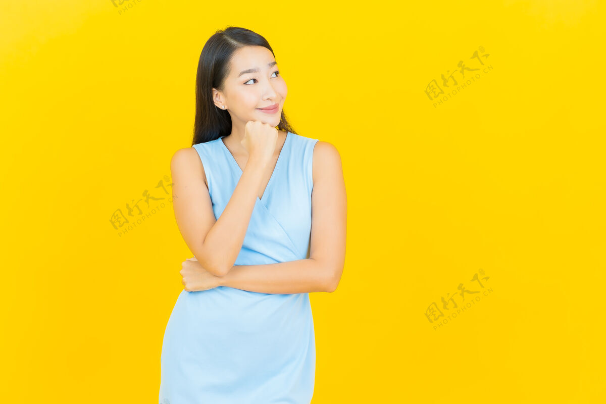 时尚在黄色墙壁上描绘美丽的亚洲年轻女子微笑的动作脸Swoosh漂亮