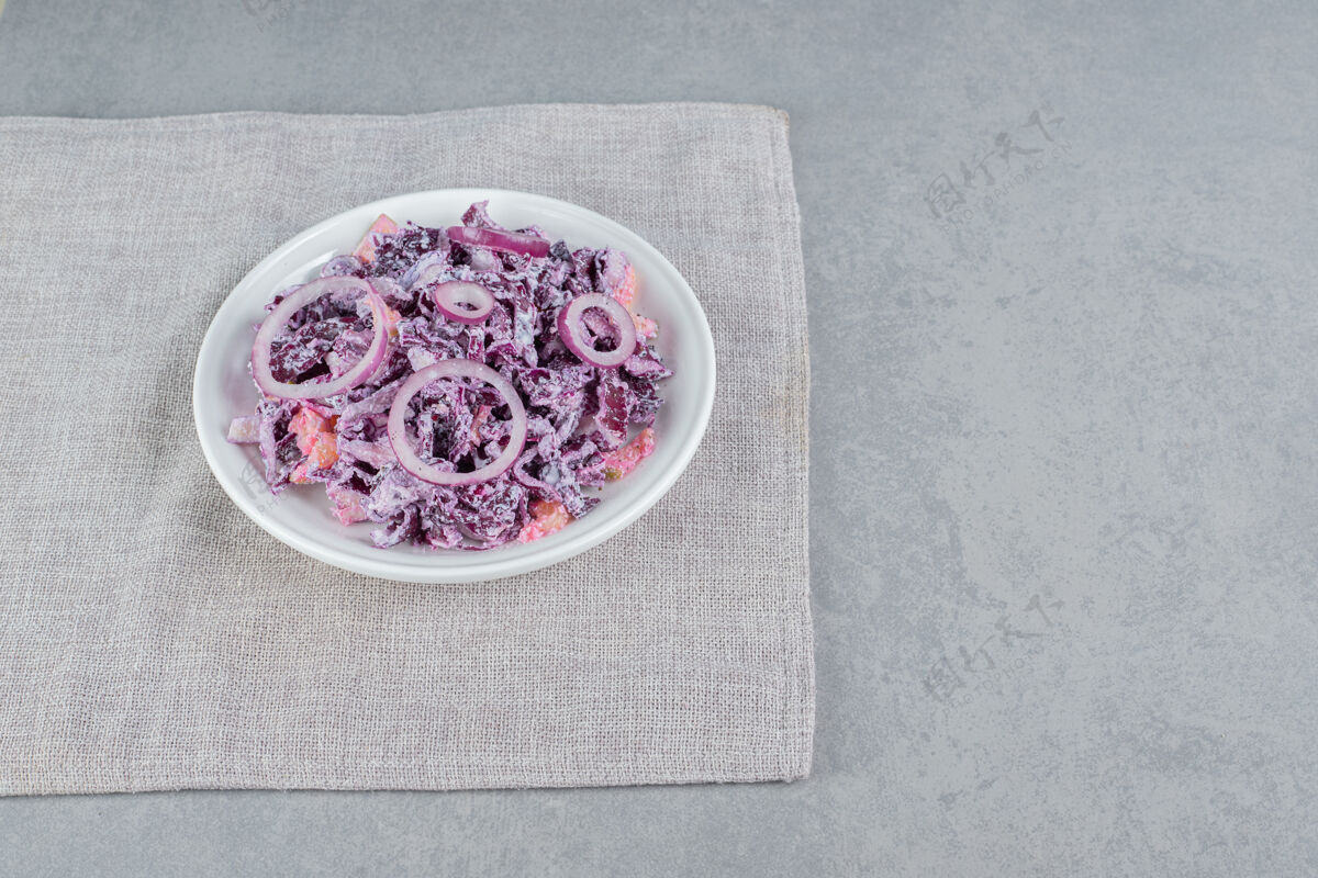 早午餐紫色卷心菜和洋葱沙拉放在白色陶瓷盘子里餐具膳食剁碎