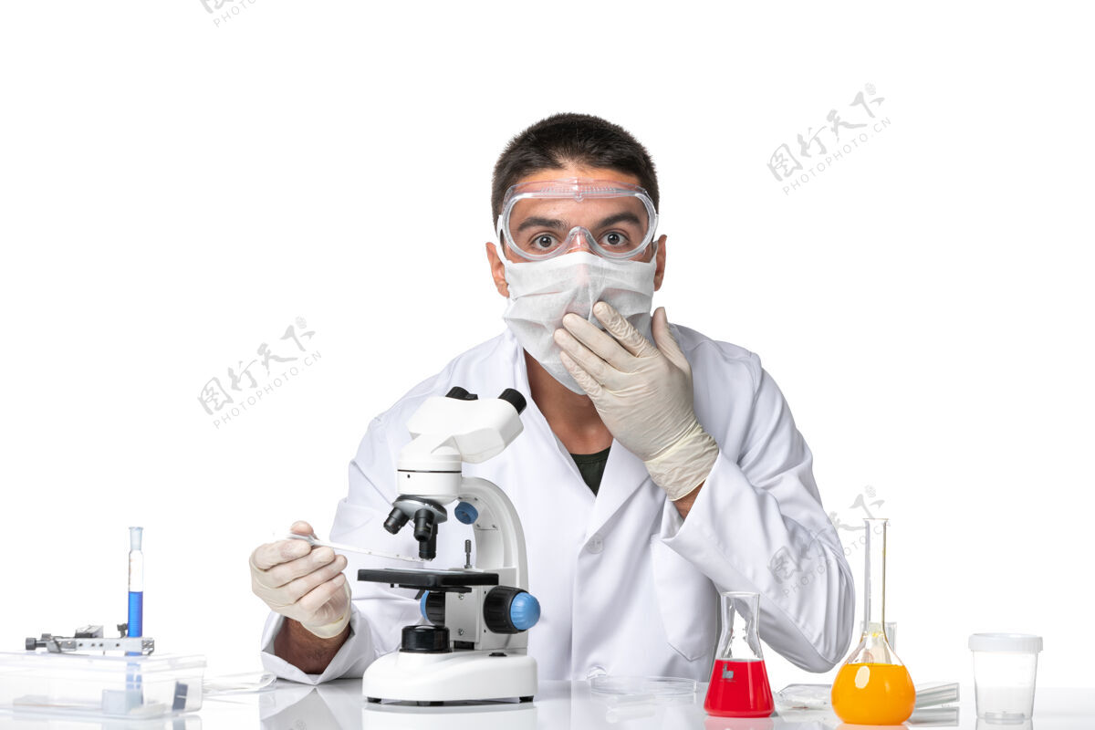 面罩正面图：男医生穿着白色医疗服 戴着面罩 戴着隐形眼镜 在浅白的空间里使用显微镜套装医学视图