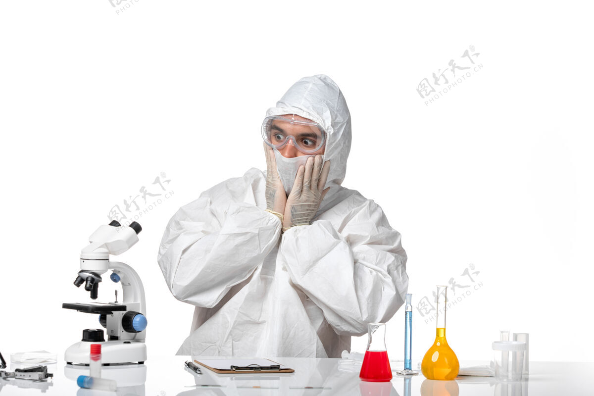 人正面图：男医生穿着防护服 戴着面具 白色桌子上的科维德表情很惊讶男医生病毒视图