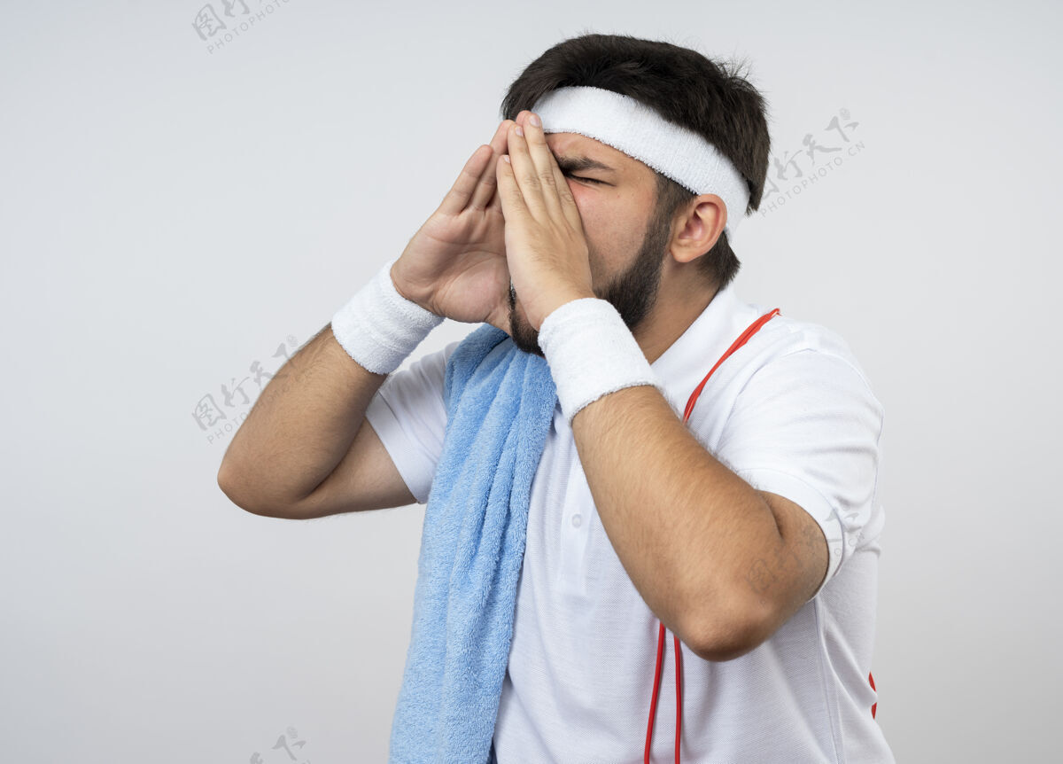 呼叫年轻的运动型男子 戴着头带和手环 肩上系着毛巾和跳绳 他闭着眼睛 在白墙上呼唤着一个孤独的人穿头带运动