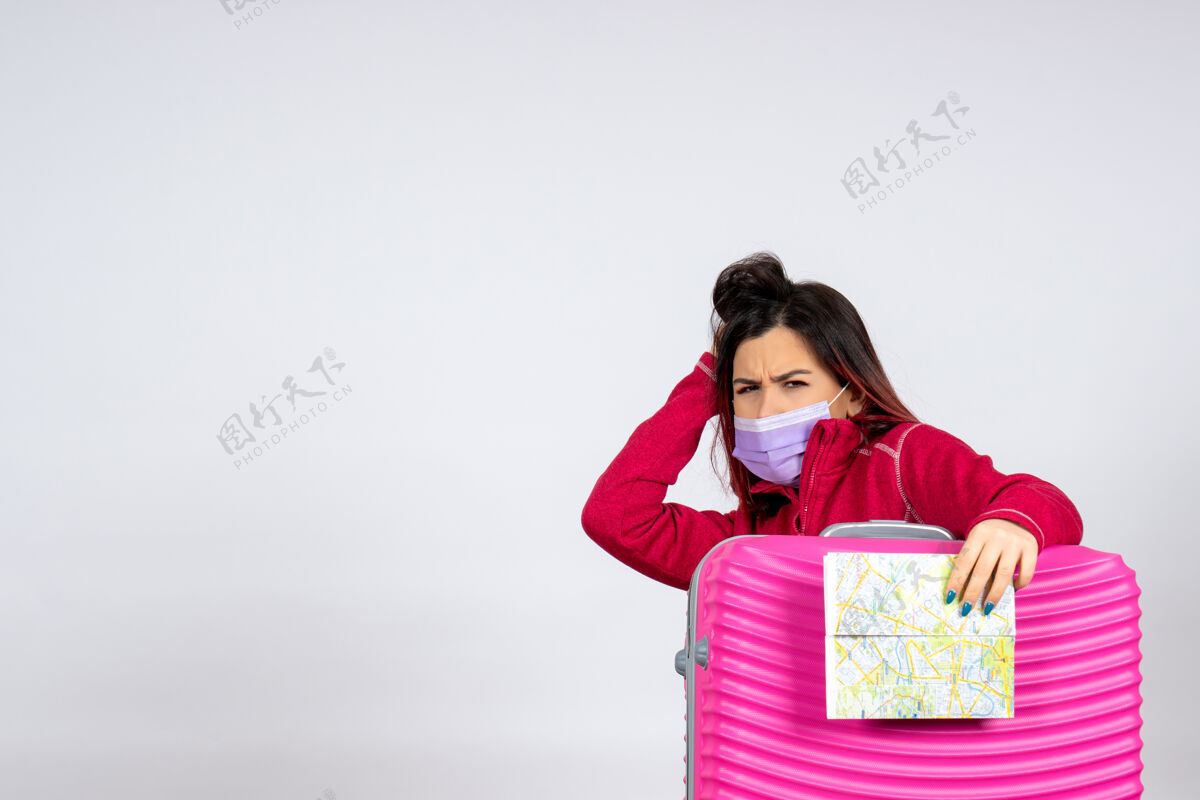颜色正面图年轻女性戴着粉红色的面具拿着白色墙壁上的地图彩色病毒度假旅行女人covid-美女病毒地图