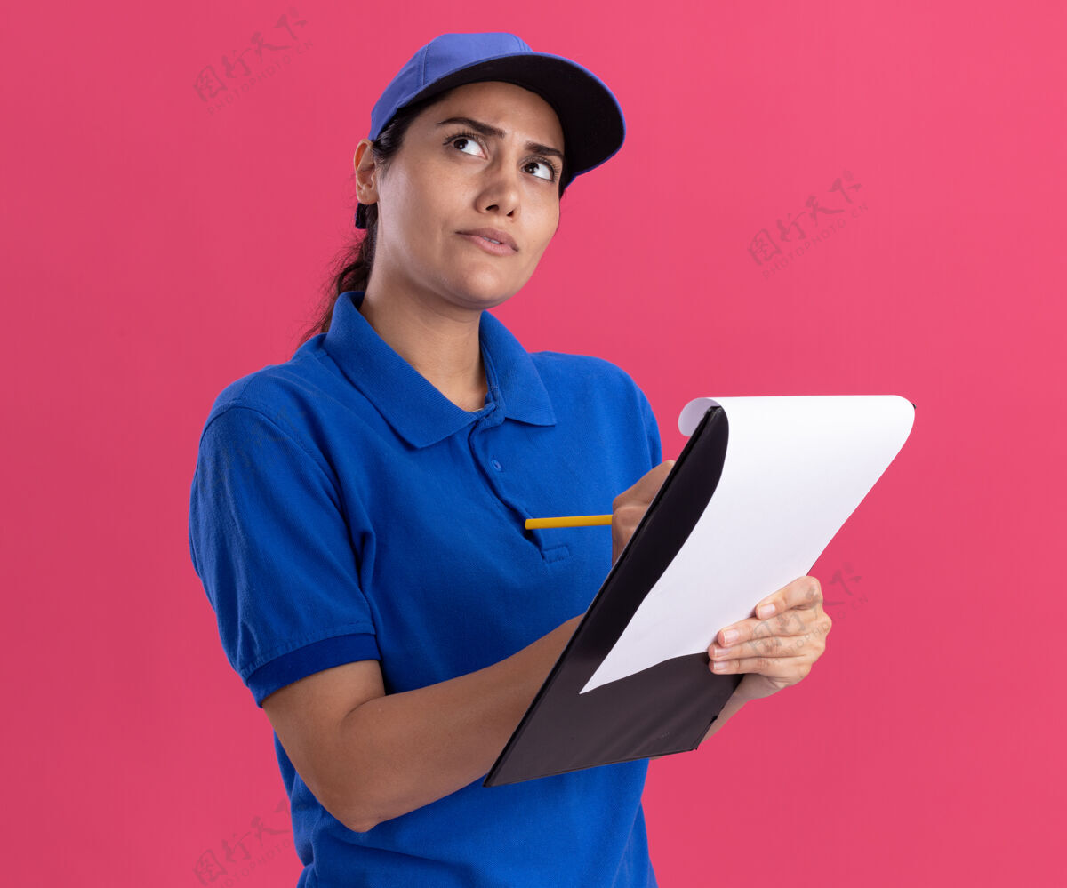 写作想想看 年轻的送货员穿着制服 戴着帽子 在粉色墙上的剪贴板上写着什么帽子女孩制服