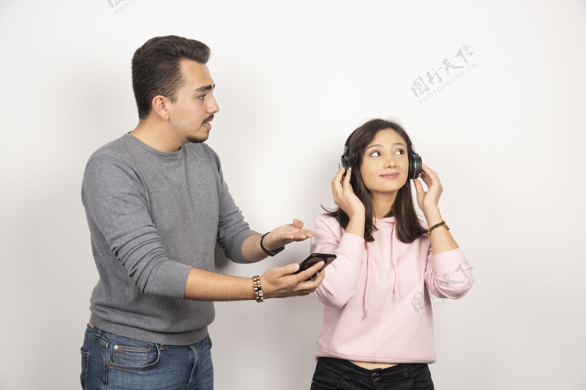 耳机年轻人试图让女人看他的手机男人电话音乐