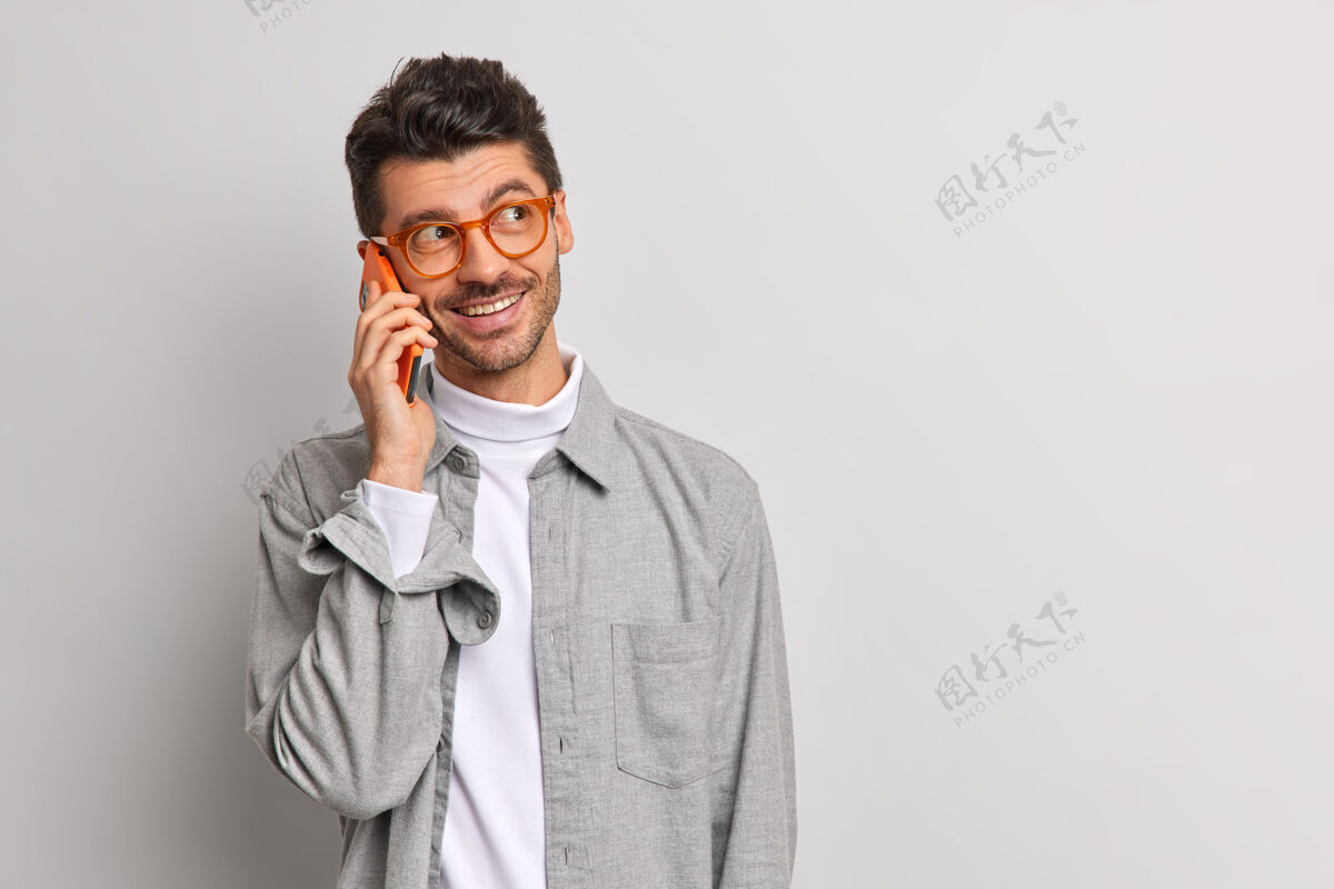 眼镜年轻帅气的男性自由职业者通过手机交谈有愉快的表情享受手机资费和连接自信眼镜高兴