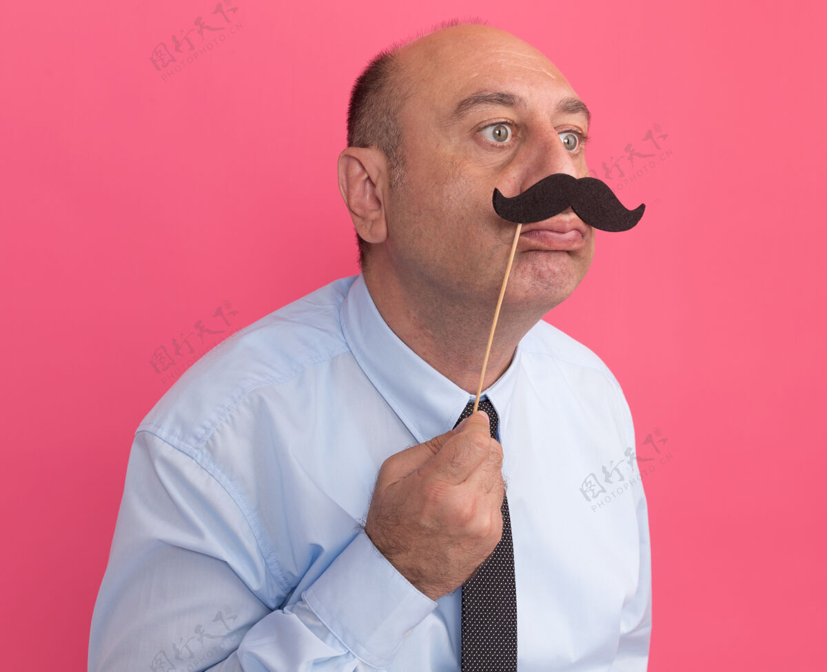 男人高兴地看着旁边的中年男子穿着白色t恤 打着领带 手里拿着假胡子 贴在粉红色的墙上请戴手领带