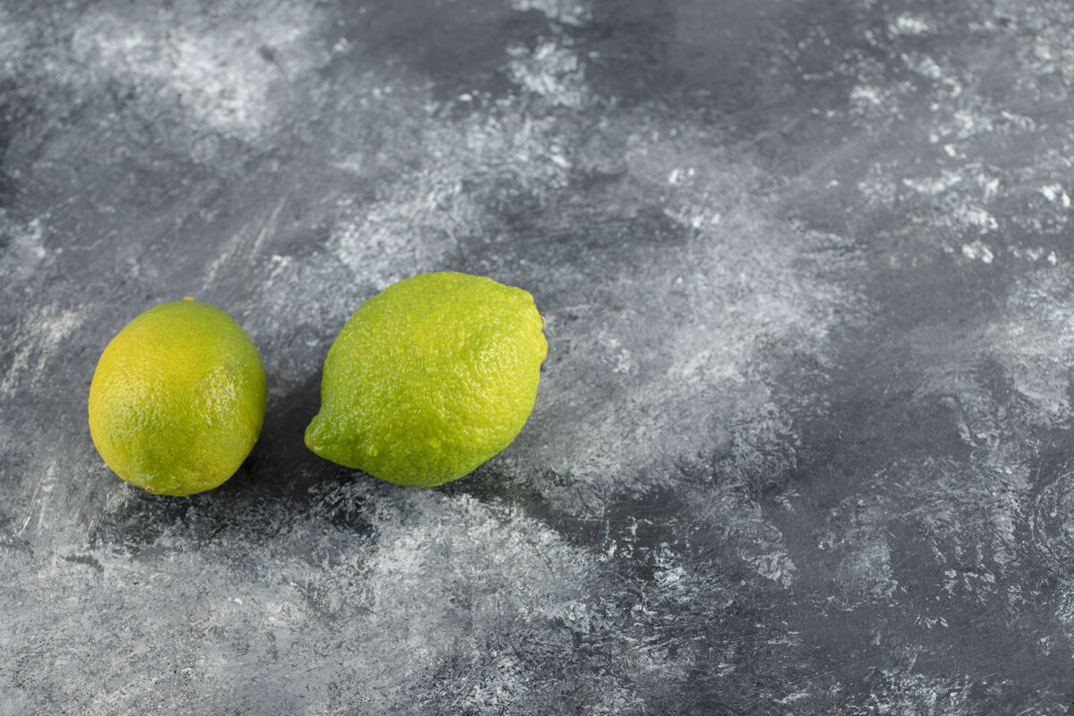 新鲜两个新鲜的绿色柠檬放在大理石表面上美味食品纤维食品