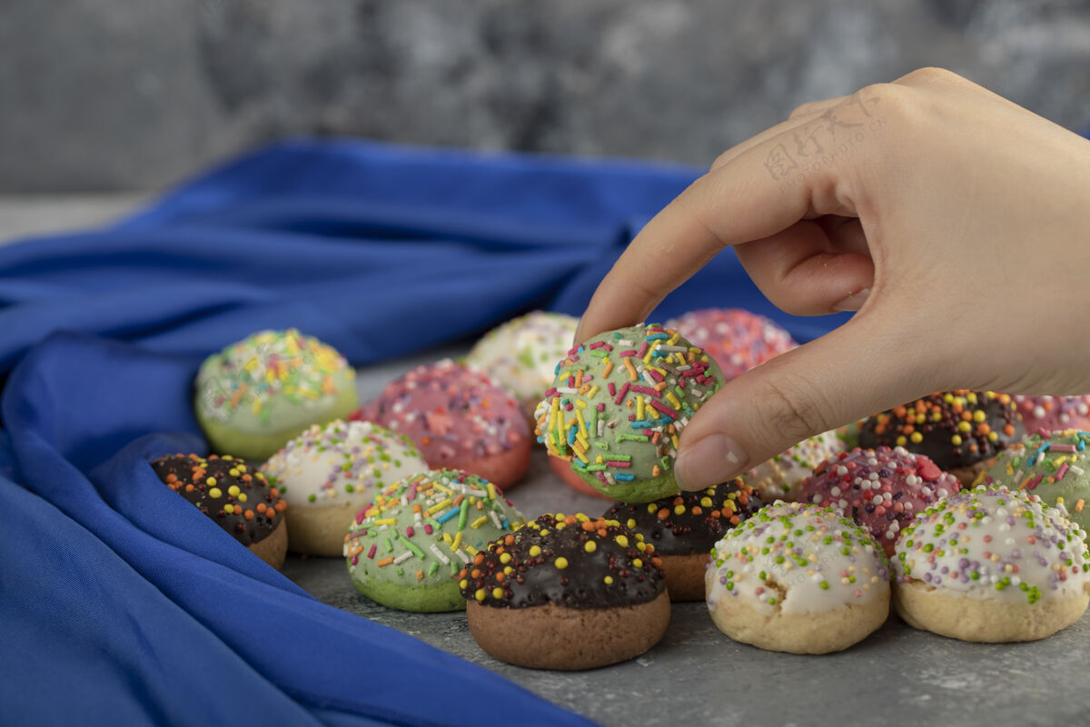 不同女人手里拿着五颜六色的小甜甜圈许多不健康食物