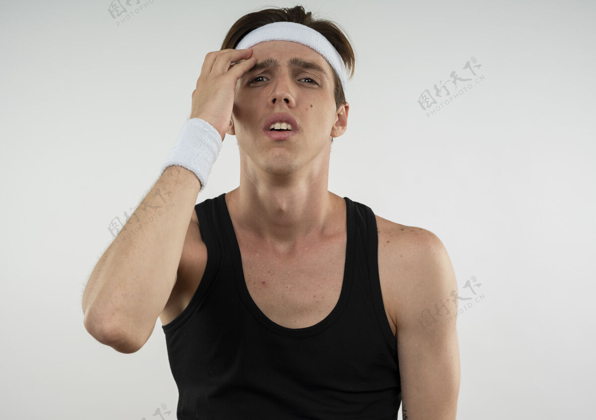 不愉快戴着头带和腕带 手放在额头上 与白色隔离的年轻运动型男子戴年轻额头