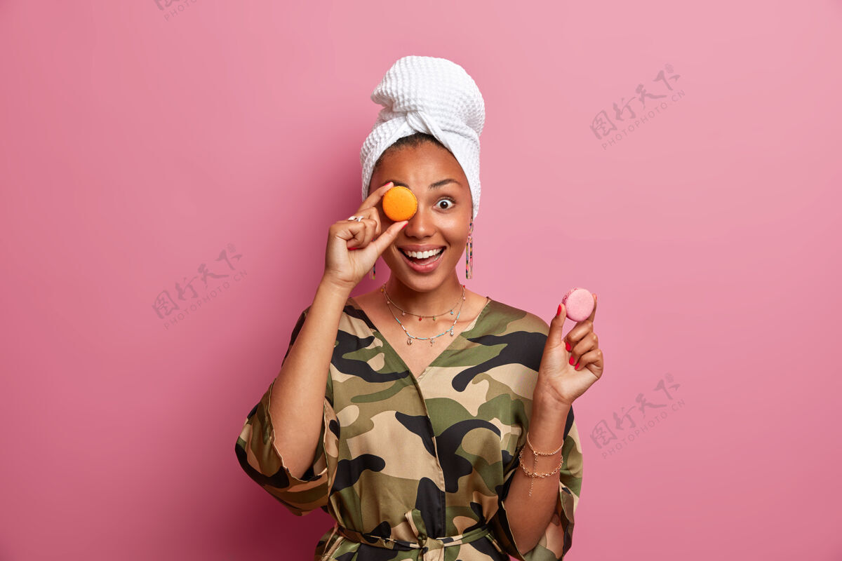 一个积极的黑皮肤女人拿着美味的杏仁饼甜点美味食物