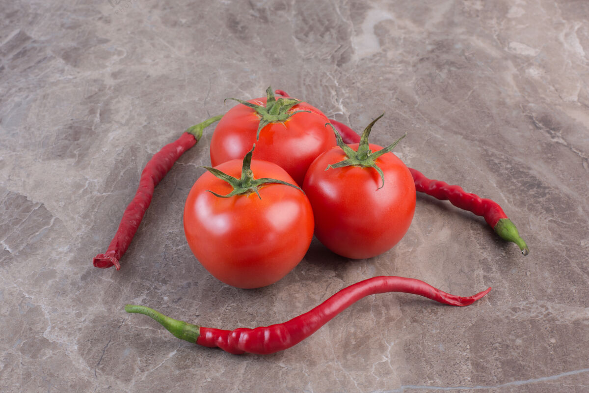 有机一小捆西红柿被三个辣椒围在大理石表面配料辛辣素食