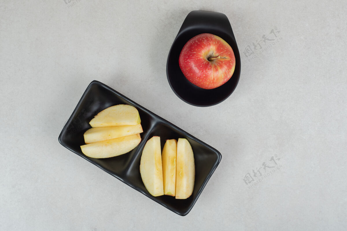 生的把整个苹果和几片红苹果放在黑色盘子里新鲜美味切片