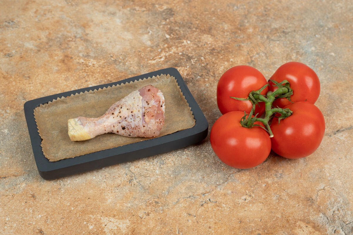 美味一块黑木板 上面有生鸡腿和西红柿西红柿板蔬菜