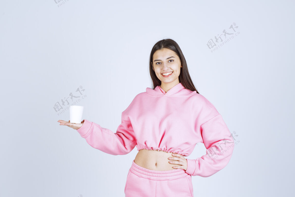 成人穿着粉色睡衣的女孩拿着咖啡杯指着什么东西人类人积极