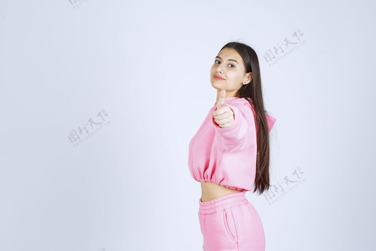 积极穿粉红色睡衣的女孩竖起大拇指享受装备精细
