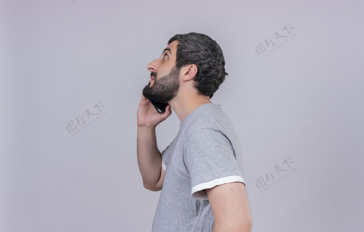 个人资料年轻英俊的白种人站在侧视图中抬头看电话 在白色背景上 有复印空间电话年轻帅哥