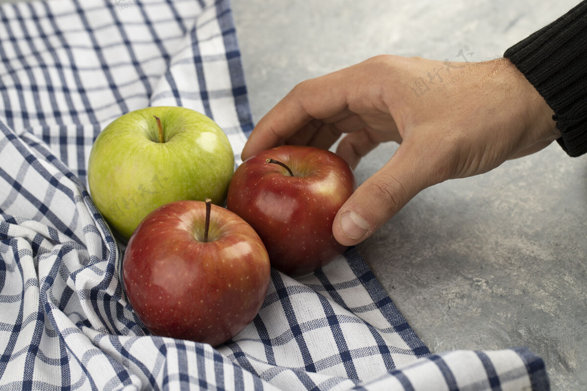 营养男性手从大理石上拿新鲜的红苹果完整水果人