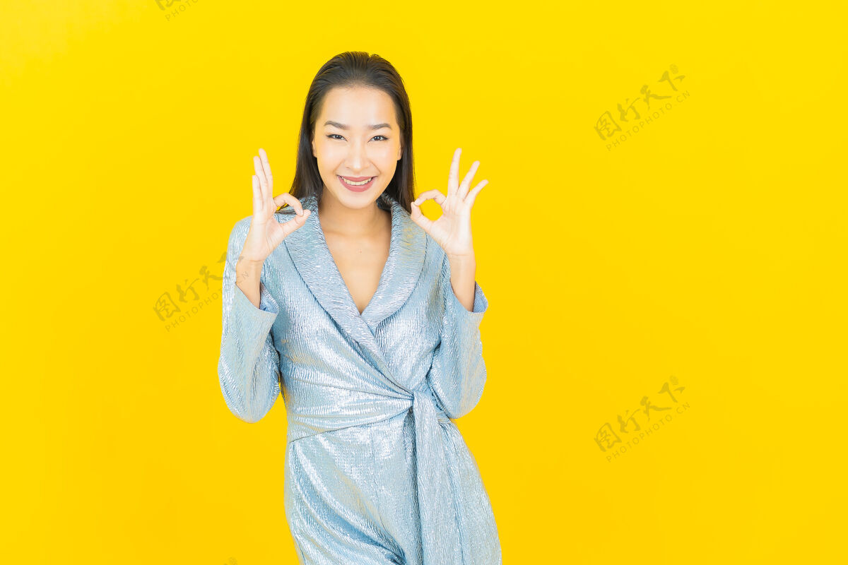 成人在黄色的墙上描绘美丽的亚洲年轻女子微笑着行动人欢乐黑发