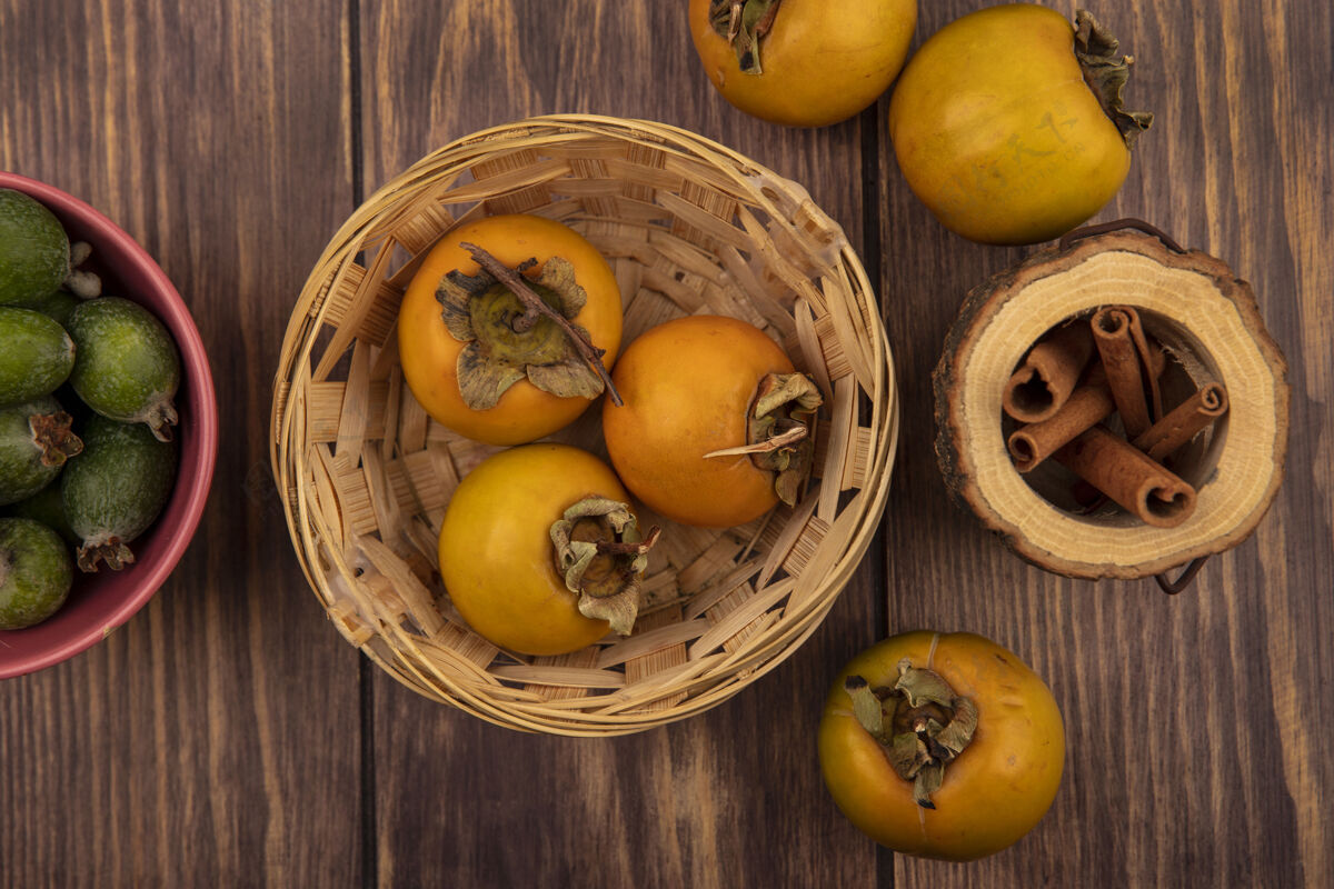 木材新鲜柿子水果在木桶上的俯视图 肉桂棒放在木制背景上的木罐上食品肉桂柿子