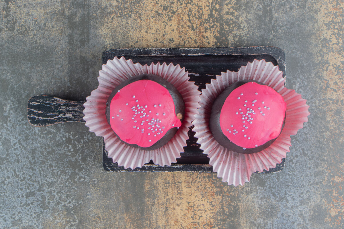 圆两个甜甜的巧克力甜甜圈 上面撒着粉色的糖霜和花洒霜冻食物糖果