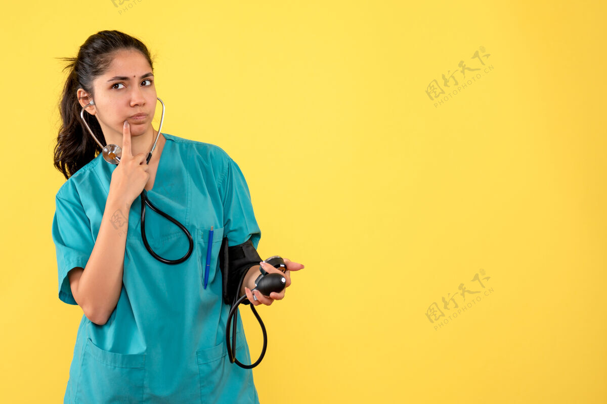 成人正面图身着制服的女医生手持血压计站着年轻女医生血压计