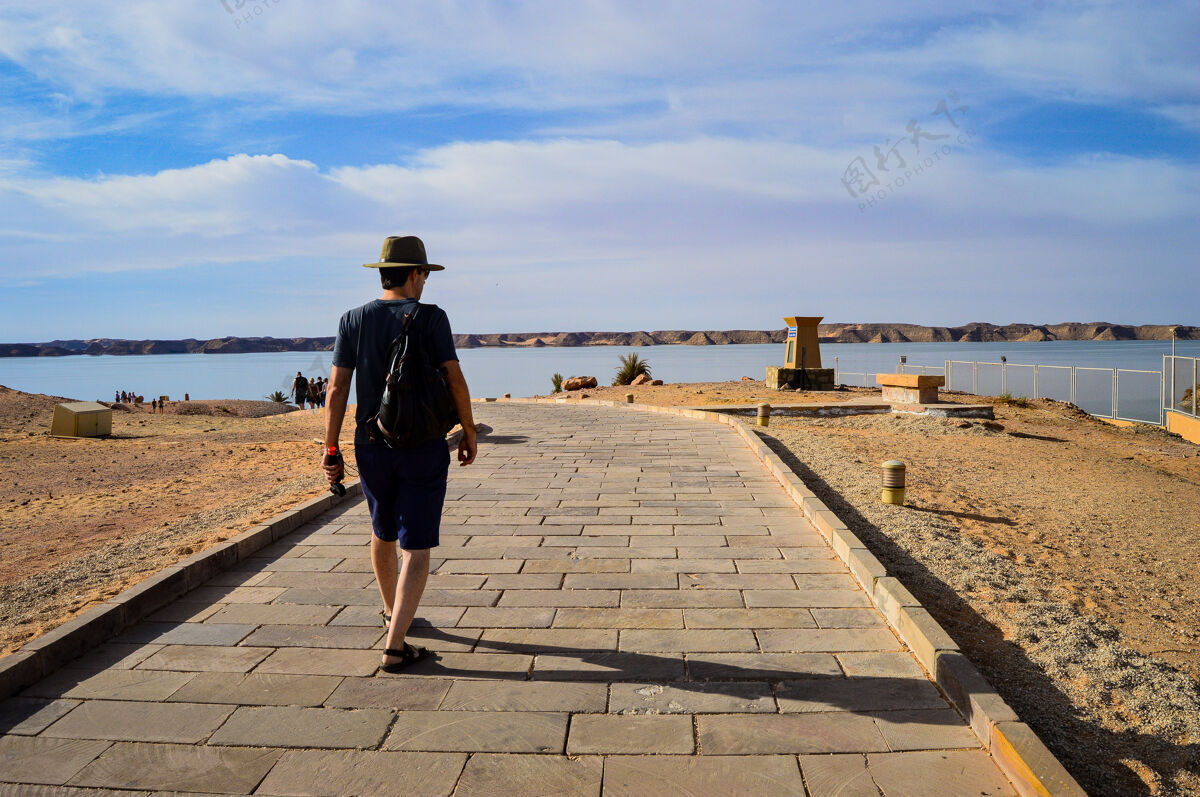 海洋特写镜头一个男人走在海边的道路上在一个阳光明媚的日子年轻沙滩阳光
