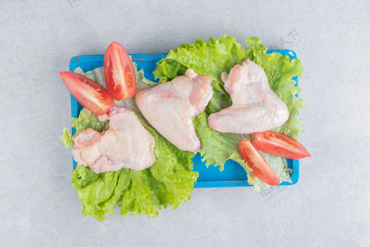 家禽把西红柿片和肉放在莴苣上 放在木板上 放在白色的表面上盘子绿色生的