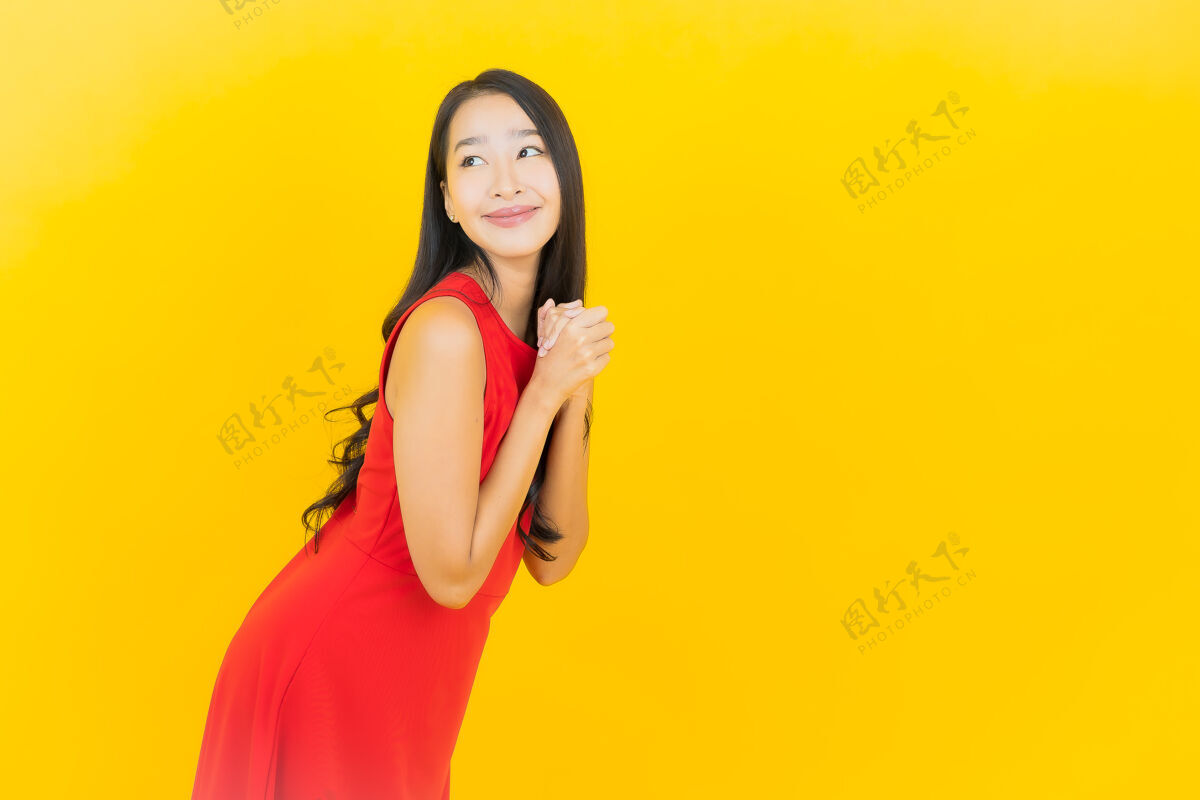 女孩肖像美丽的亚洲年轻女子穿着红色连衣裙微笑着行动在黄色的墙上人多彩年轻