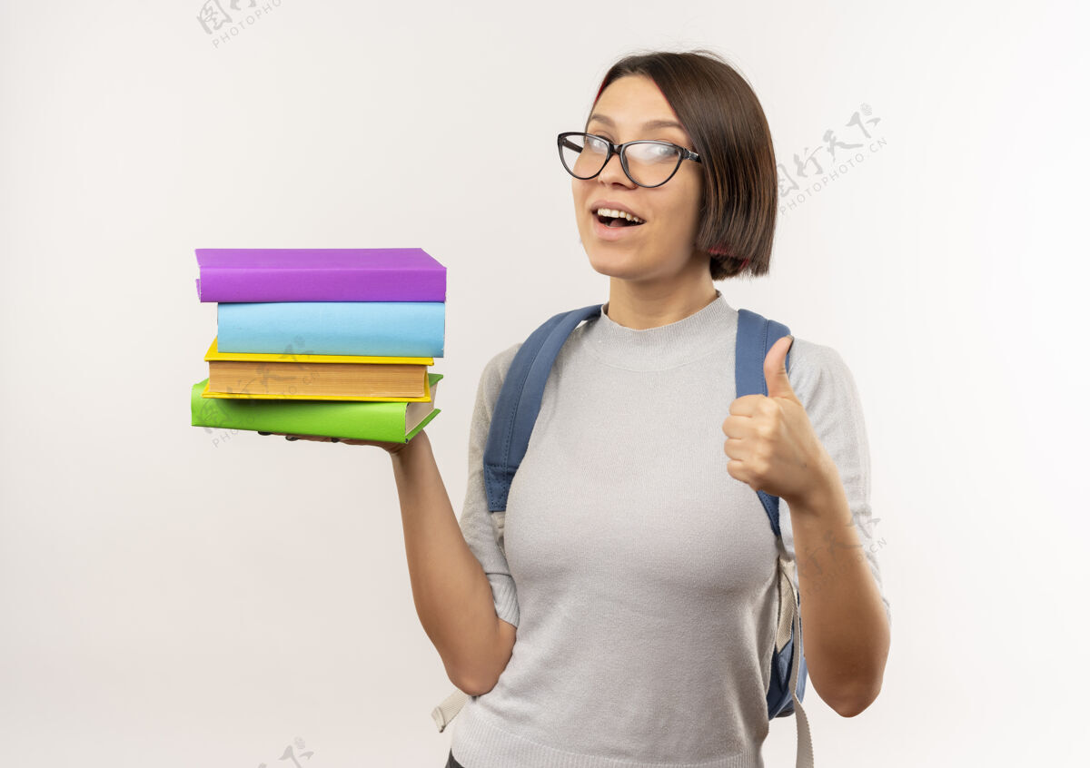 背给人印象深刻的年轻女学生戴着眼镜 背着书包 在白色的地板上竖起大拇指拿着印象展示