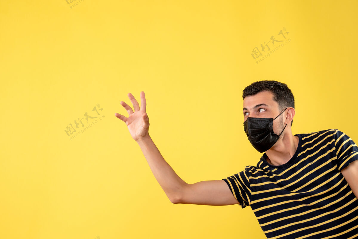 人正面图戴着黑色面具的帅哥在黄色孤立的背景上招呼某人成人冰雹肖像
