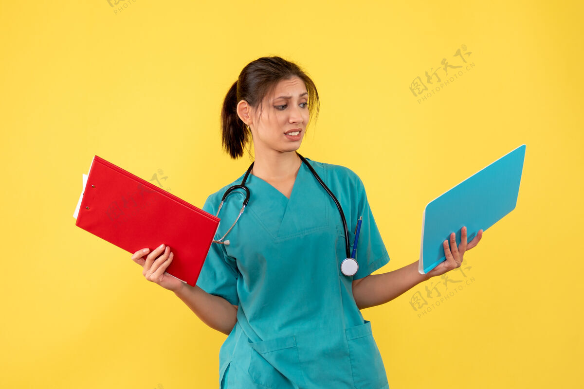 健康正面图黄色背景下穿着医用衬衫的女医生拿着分析肖像正面黄色