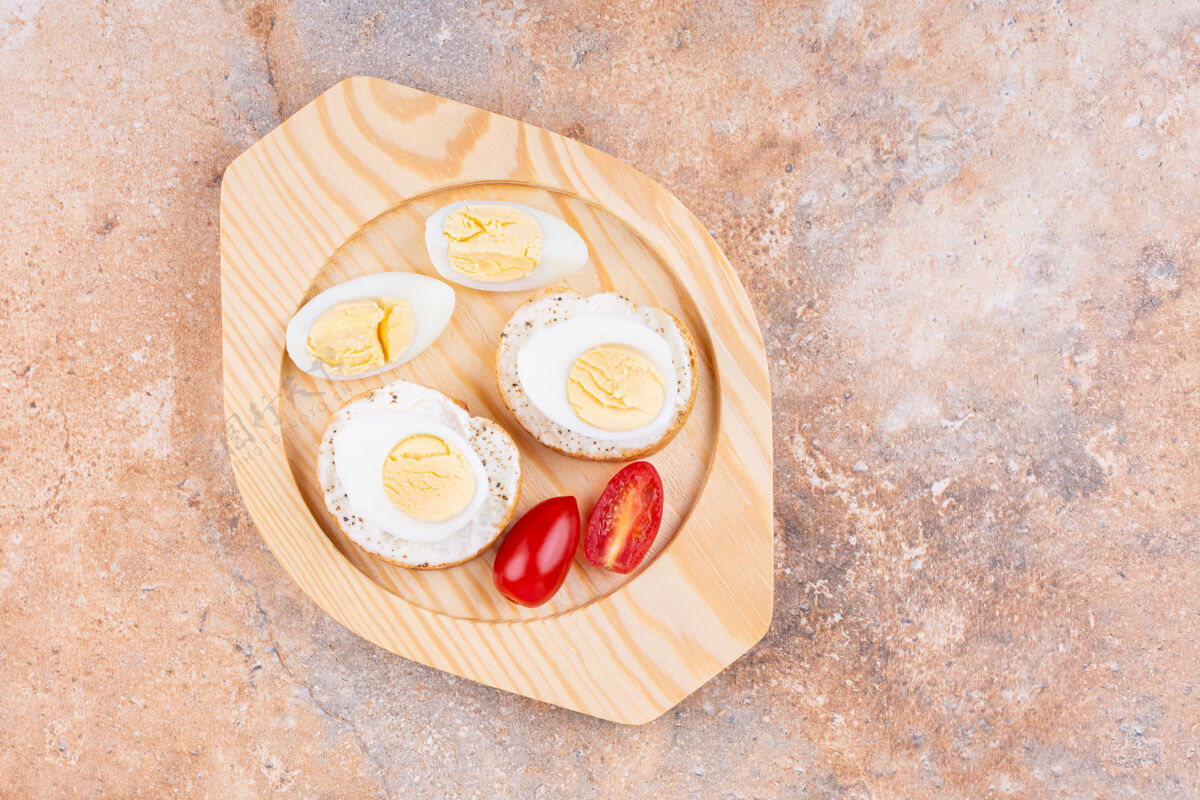面包房把煮熟的鸡蛋切片 西红柿和面包放在木盘上 放在大理石上谷物外壳面粉