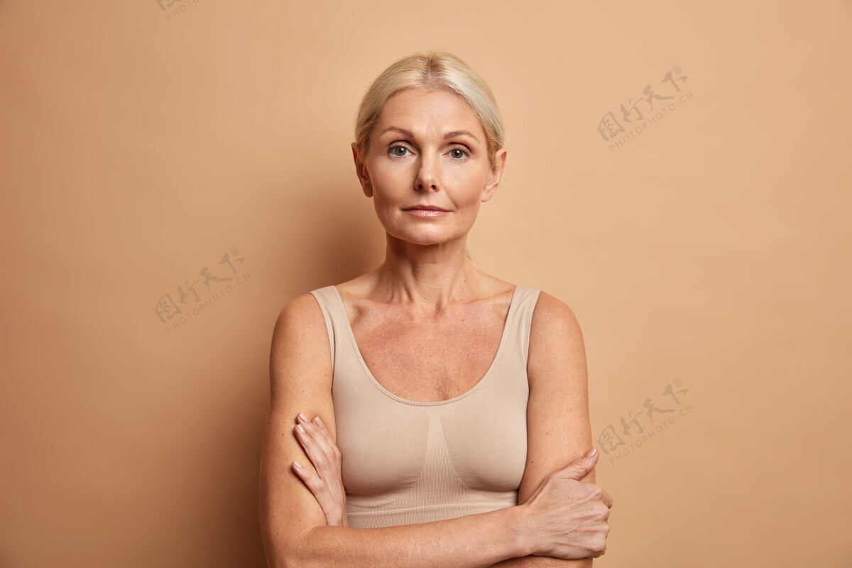 提升迷人的皱纹女人交叉双臂摆姿势的肖像健康皱纹年龄