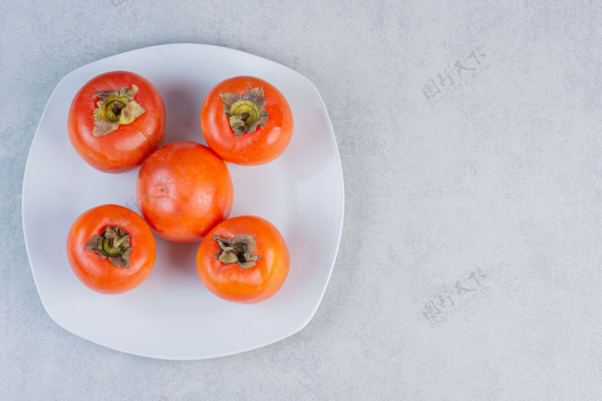 水果白色盘子上的橙色柿子特写照片食物自然盘子