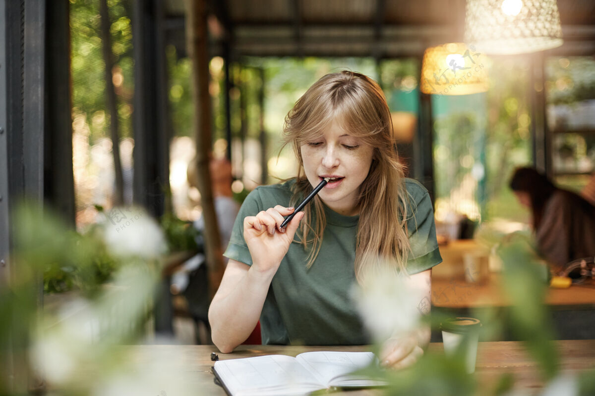 记事本年轻女学生在咖啡馆里嚼铅笔准备通过考试的画像无线科技女人