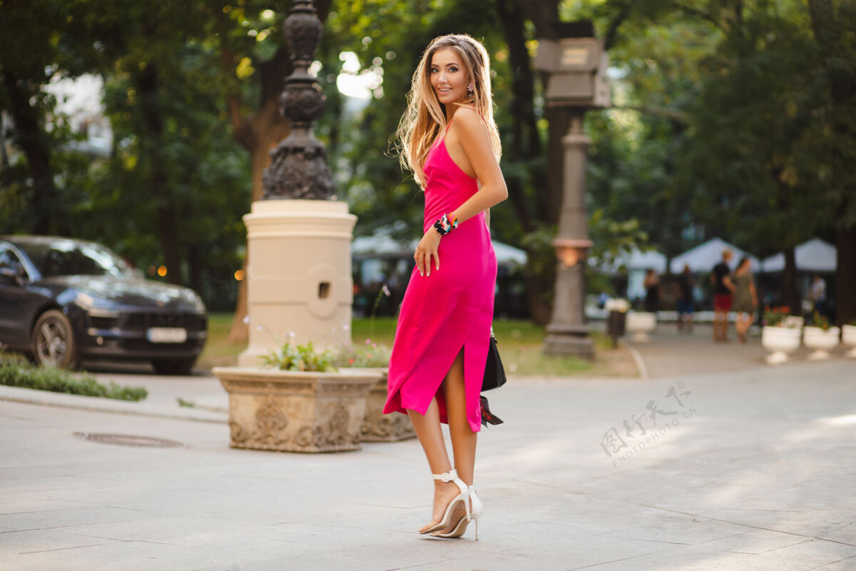 街头优雅迷人的女人穿着粉色性感夏装 手拿手袋走在街上华丽现代城市