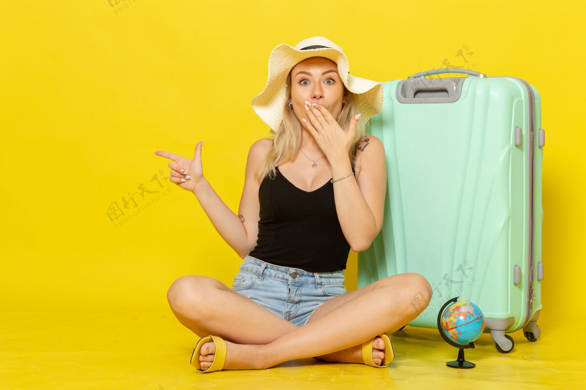 成年人正面图：年轻女子背着包坐在黄墙上旅行度假旅行阳光视野漂亮年轻