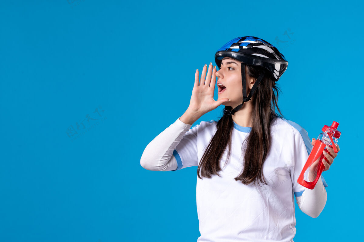 年轻女性前视图穿着运动服的年轻女性 蓝色墙上戴着头盔瓶子水平人