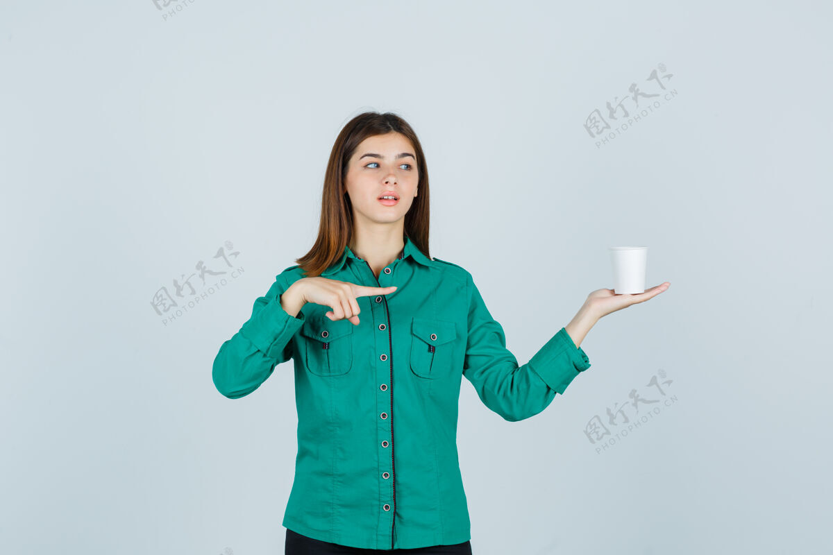 而穿着衬衫的年轻女士手里拿着一杯塑料咖啡 同时指向右边 目光集中 俯视前方女人年轻女性