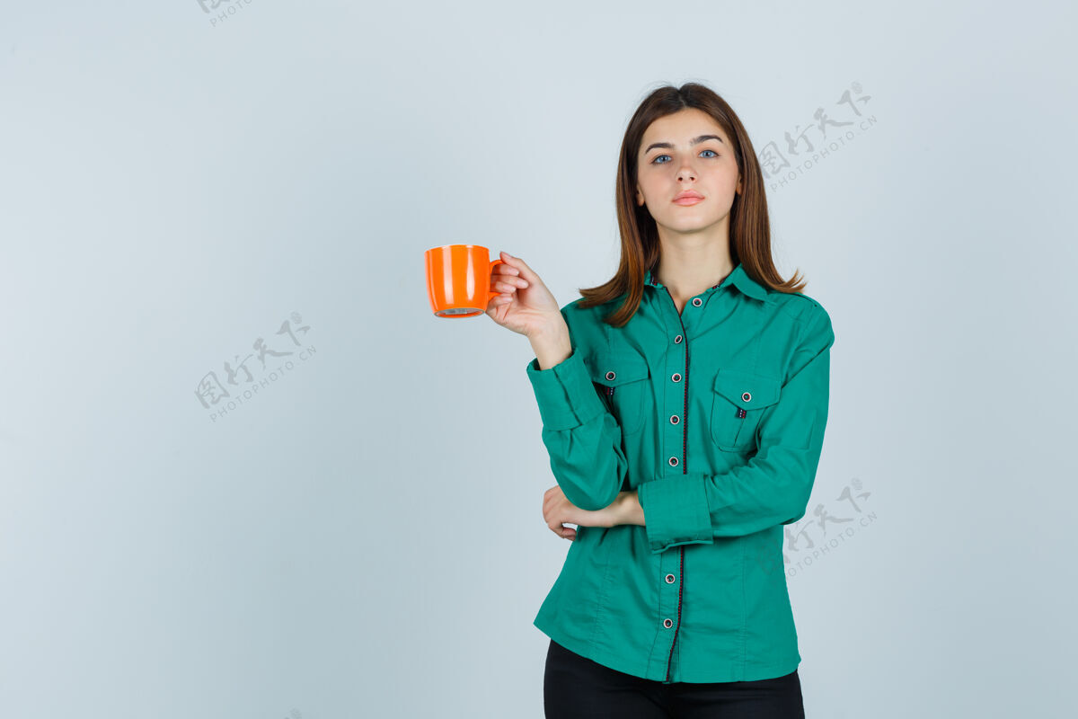 举行穿着衬衫的年轻女士手里拿着一杯橘色的茶 看上去很自信 正对着前方女士成人沙龙