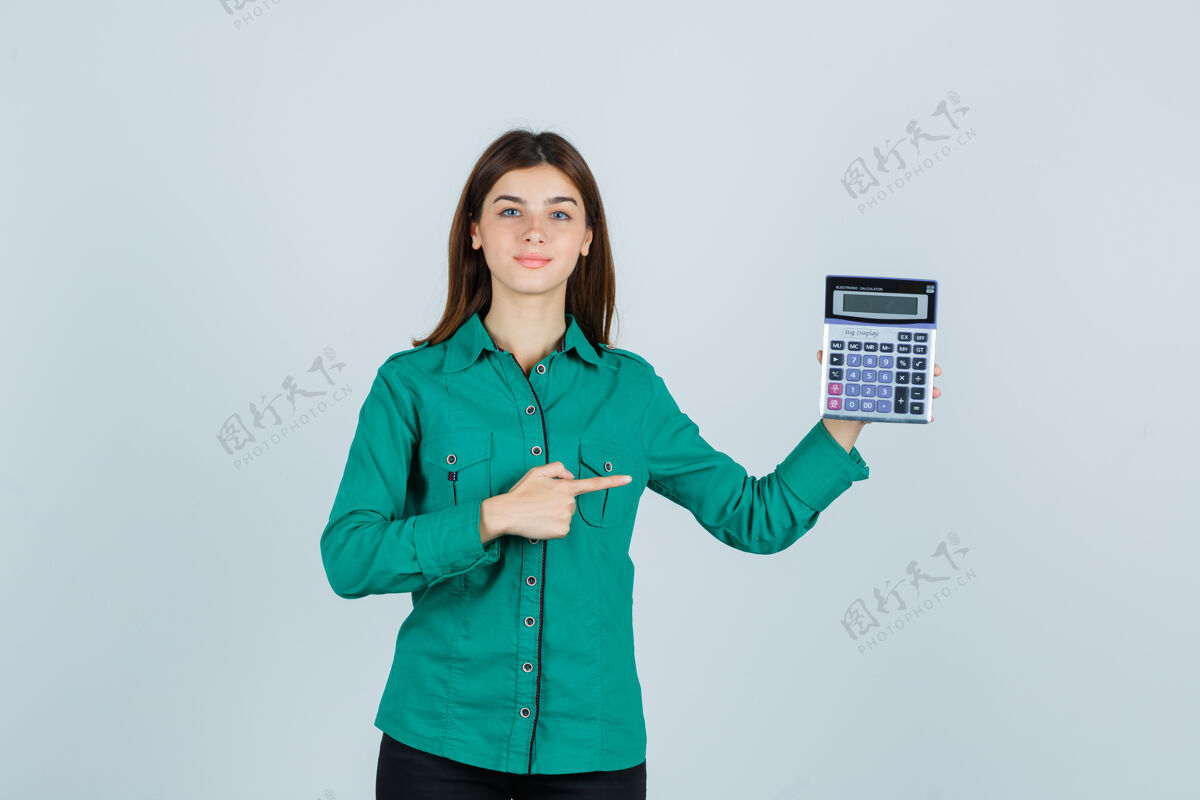 商务穿着绿色衬衫的年轻女士指着计算器 看起来很自信正视图漂亮专业商务女性