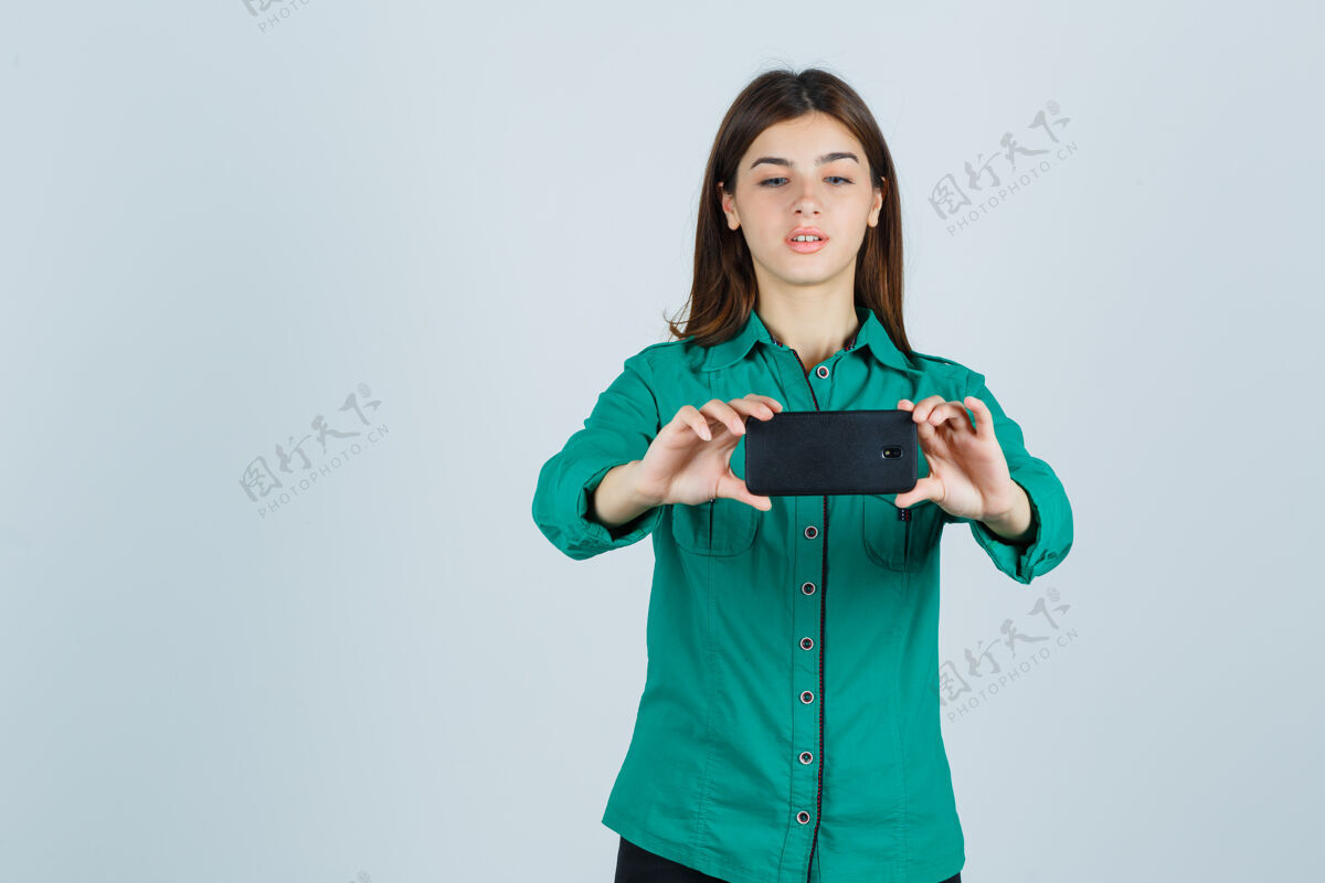 后视图穿着绿色上衣 黑色裤子的年轻女孩在自拍 看起来很专注前视图拍摄电脑课教育