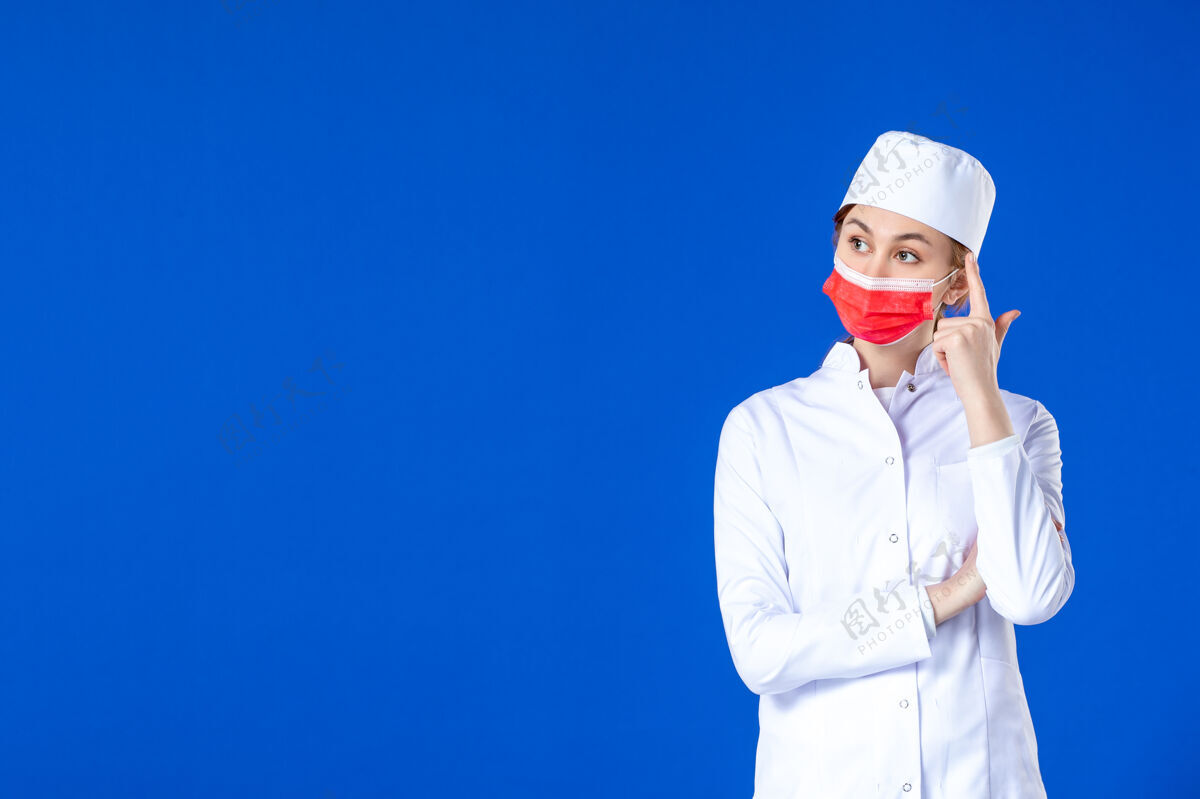 大流行正面图身着医疗服的年轻护士 蓝色墙上戴着红色防护面具防护病毒面罩