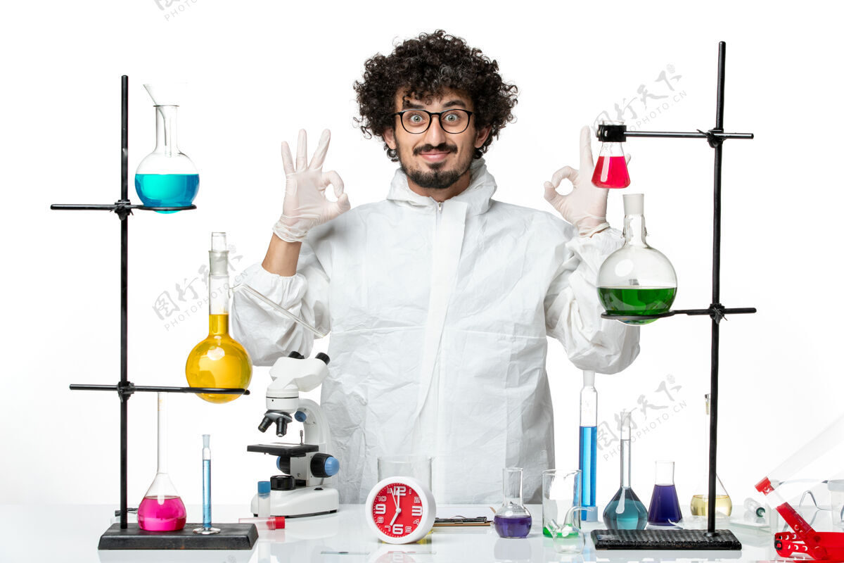 实验正面图身着白色特制西服的年轻男科学家站在桌子旁 面带微笑医学视图玻璃